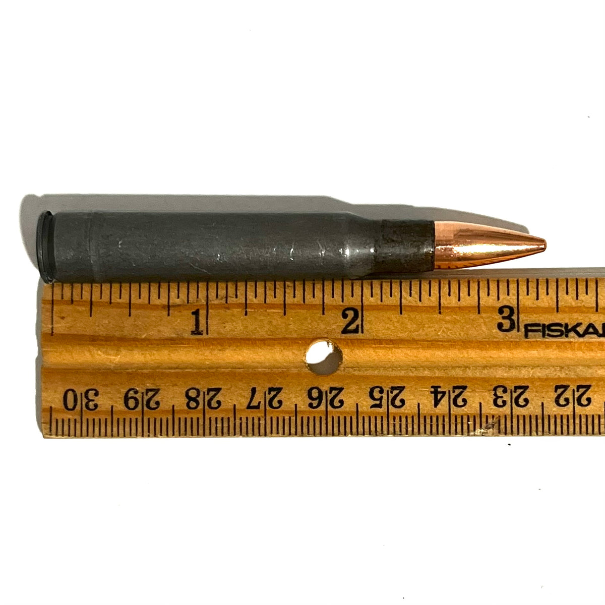 Steel 30-06 dummy rifle round with a copper bullet measured on a wood ruler at approximately 3.3 inches