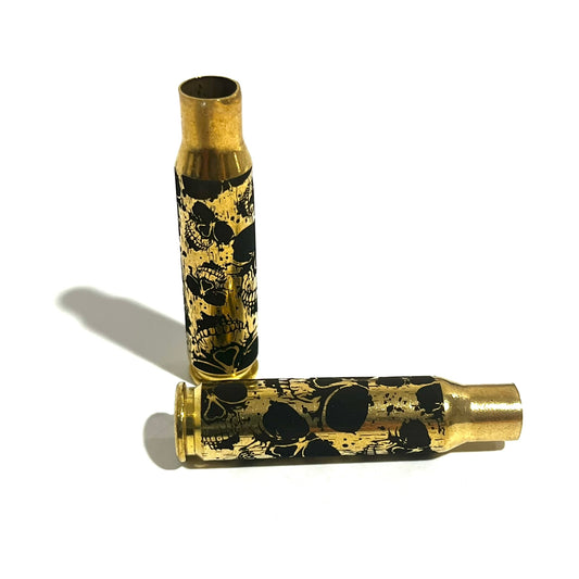 Two 308 WIN brass cartridges with laser-engraved skull graphics, one standing upright and one lying flat.