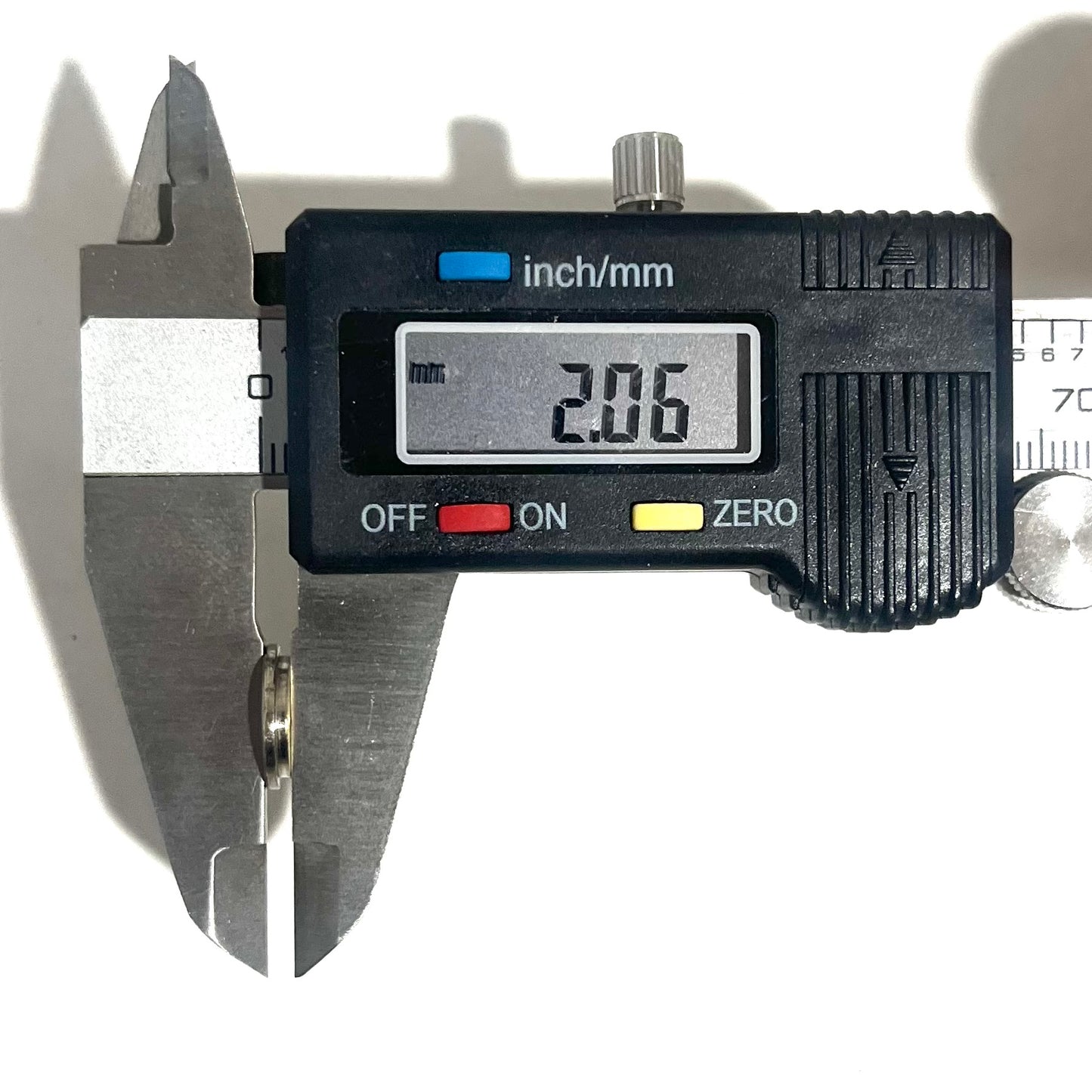 A digital caliper measuring a deprimed bullet casing slice, showing a thin-cut thickness reading of 2.06 mm.