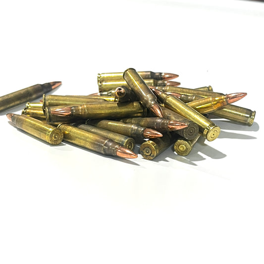 A jumbled pile of dirty .223 dummy cartridges with copper bullet tips on white background