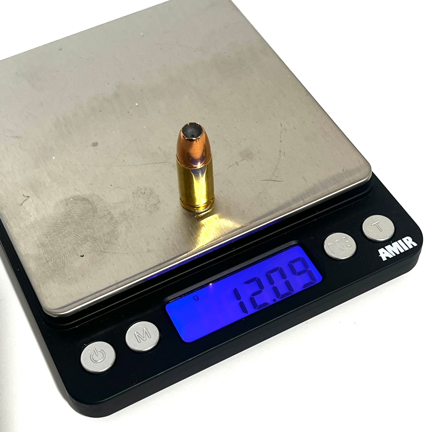 Single brass 9mm dummy round resting on a digital scale showing a weight measurement of 12.09 grams.