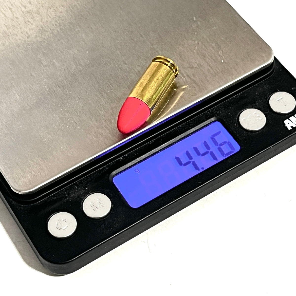 Fake 9mm Luger dummy round with red painted tip on a digital gram scale reading 4.46 grams