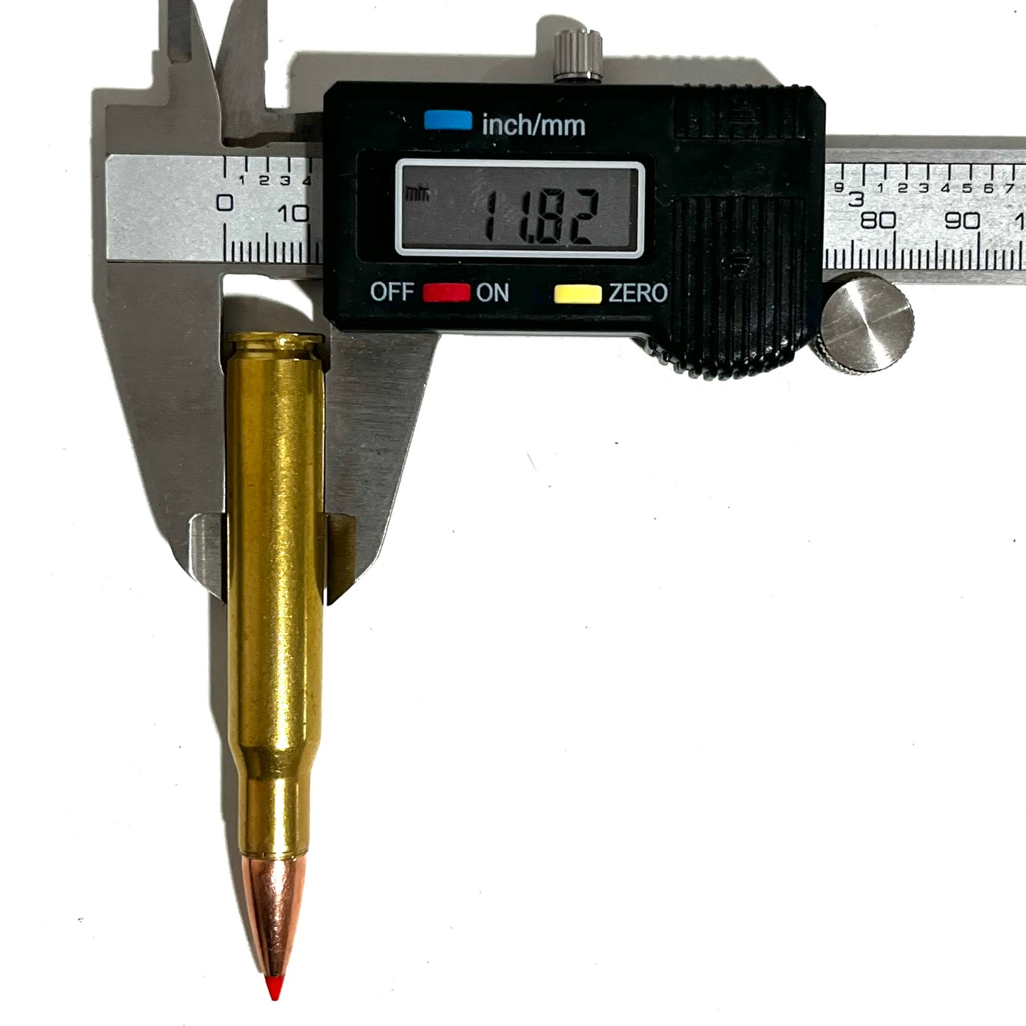 One brass red tip dummy round measured with a caliper showing 11.82 mm diameter.