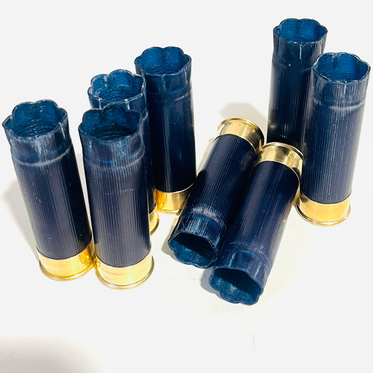 Eight once-fired dark blue 12 gauge hulls with gold bases, six standing upright and two lying with open ends forward