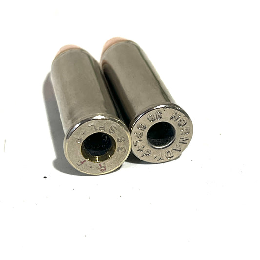 Two nickel 38 Special dummy round casings viewed base-up showing Hornady headstamps and copper flat nose bullets