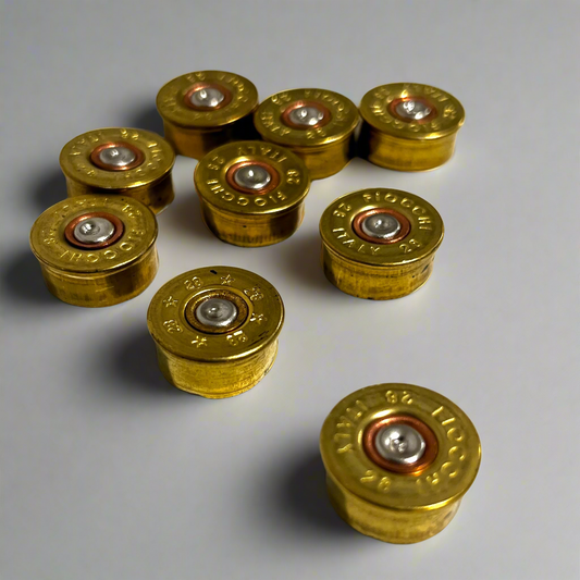Eight gold brass 28 gauge Fiocchi shotgun shell headstamps scattered in a group showing stamped text and spent primers.