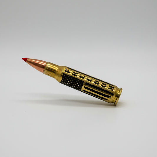 Brass .308 round with red tip lying diagonally on white, engraved with 'FREEDOM' text and flag stripes