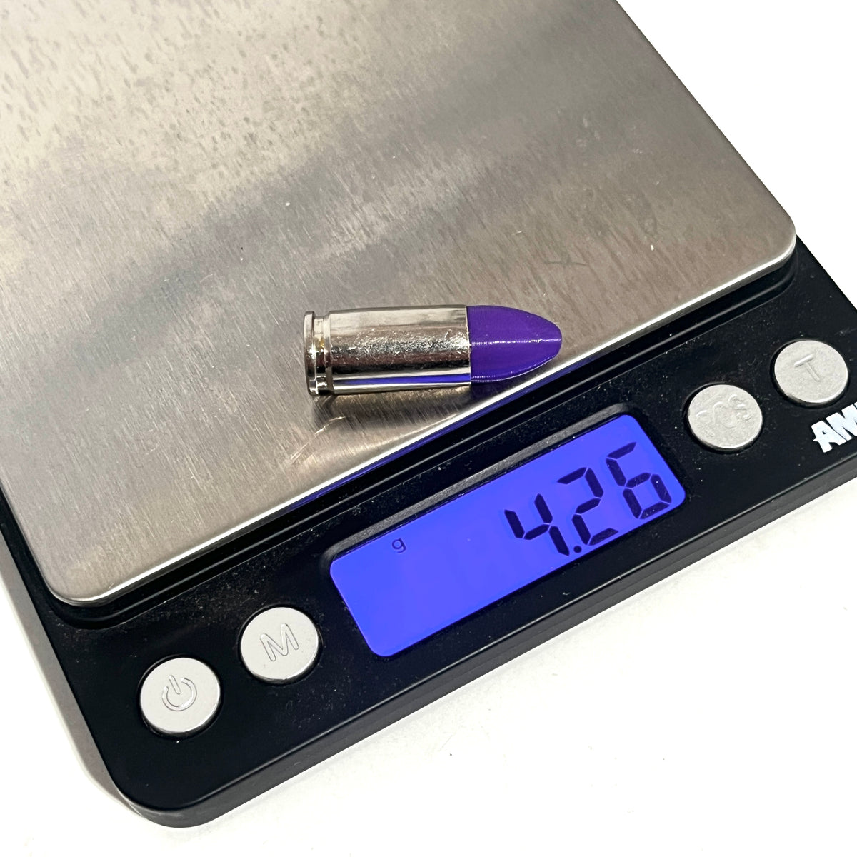 A nickel 9mm Luger cartridge with purple bullet tip on a digital gram scale showing 4.26 grams