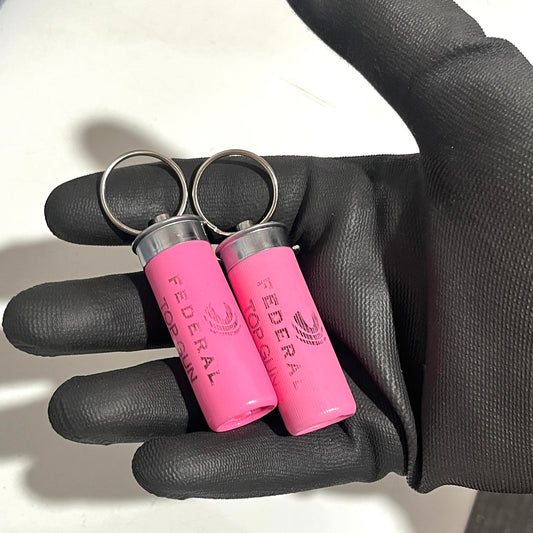 2 pink federal shotgun shell keychains with silver ring on black gloved hand