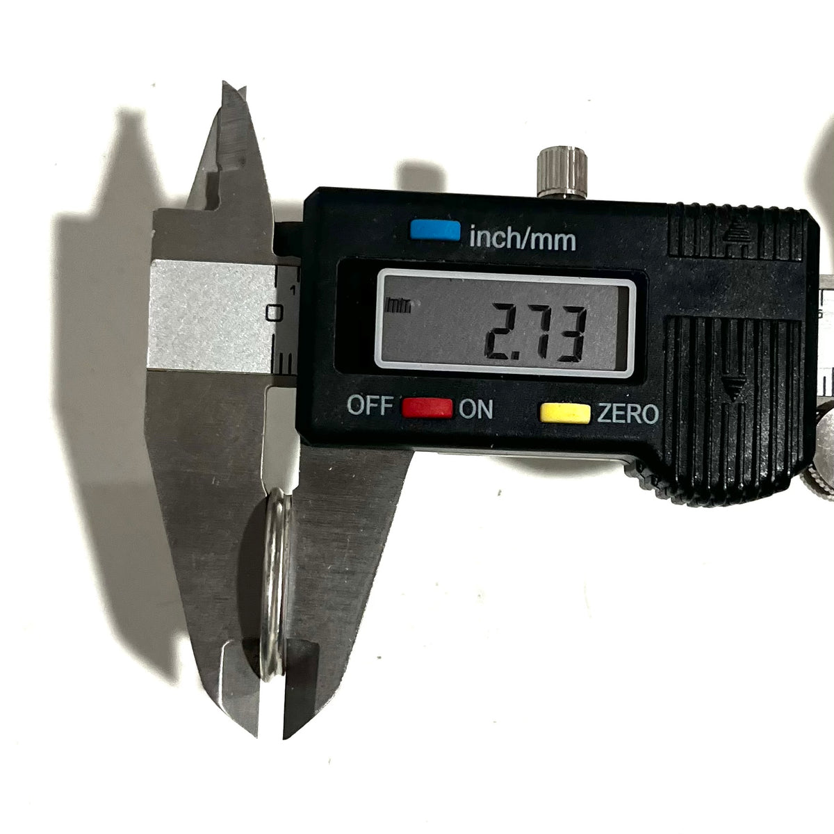 Digital caliper measuring the thickness of a silver shotgun shell slice at 2.73 mm