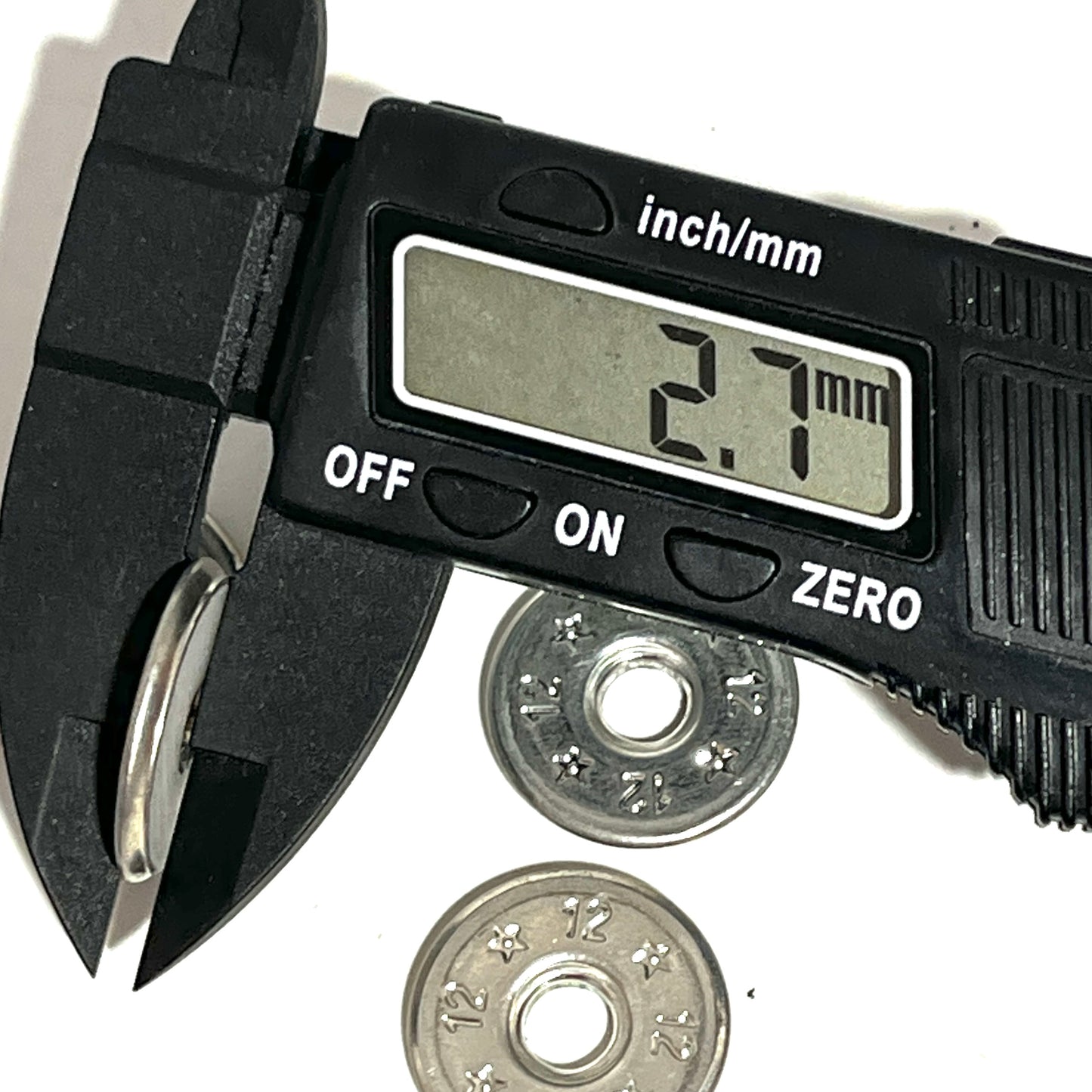 Digital caliper measuring the width of a flattened 12 gauge shotgun shell slice at 2.7mm, two more slices in background