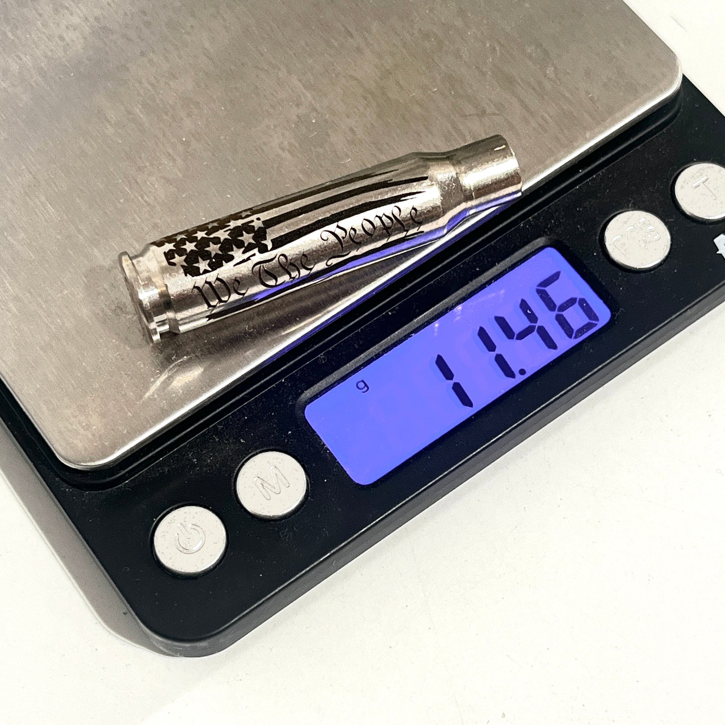Nickel .308 WIN cartridge engraved with We The People on a digital scale reading 11.46 grams