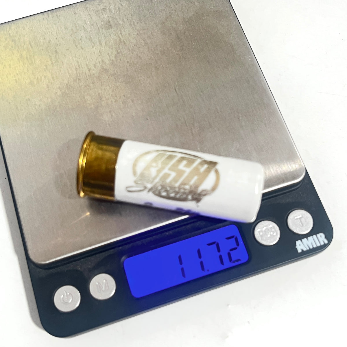 A white used hull with USA Shooting text resting on a digital scale showing a reading of 11.72.