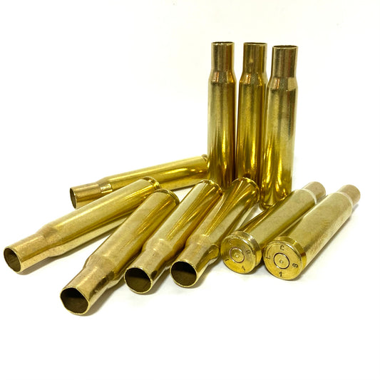 Nine polished 50 BMG casings brassarranged in a pile, some standing upright and others lying on their sides.