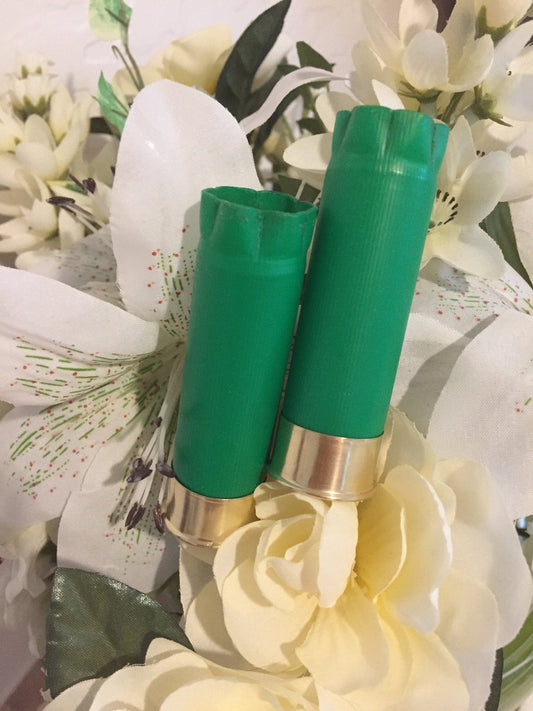 Two green Sellier and Bellot 12 gauge shotgun shells with gold brass heads standing among white flowers