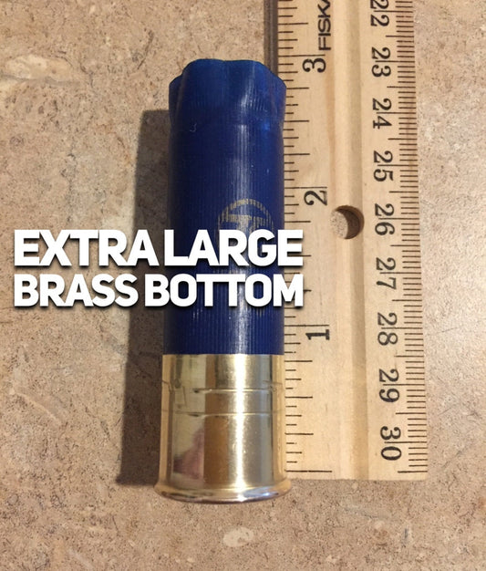 Navy blue 12 gauge shotgun shell with an extra-large brass bottom shown beside a ruler for size reference