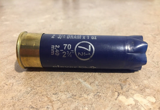 Single empty navy blue 12 gauge Clever Mirage shotgun shell with brass base on a stone surface