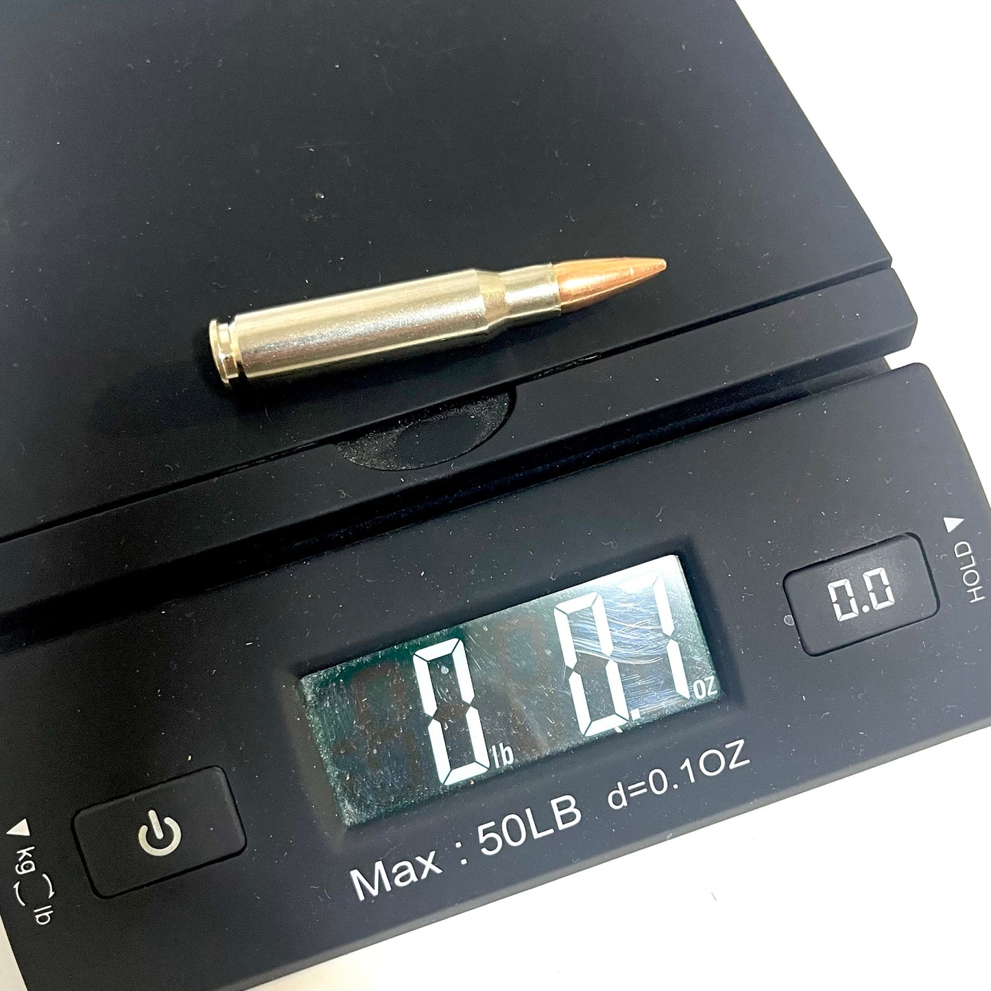 A single nickel-plated .308/7.62x51 dummy cartridge resting on top of a digital scale