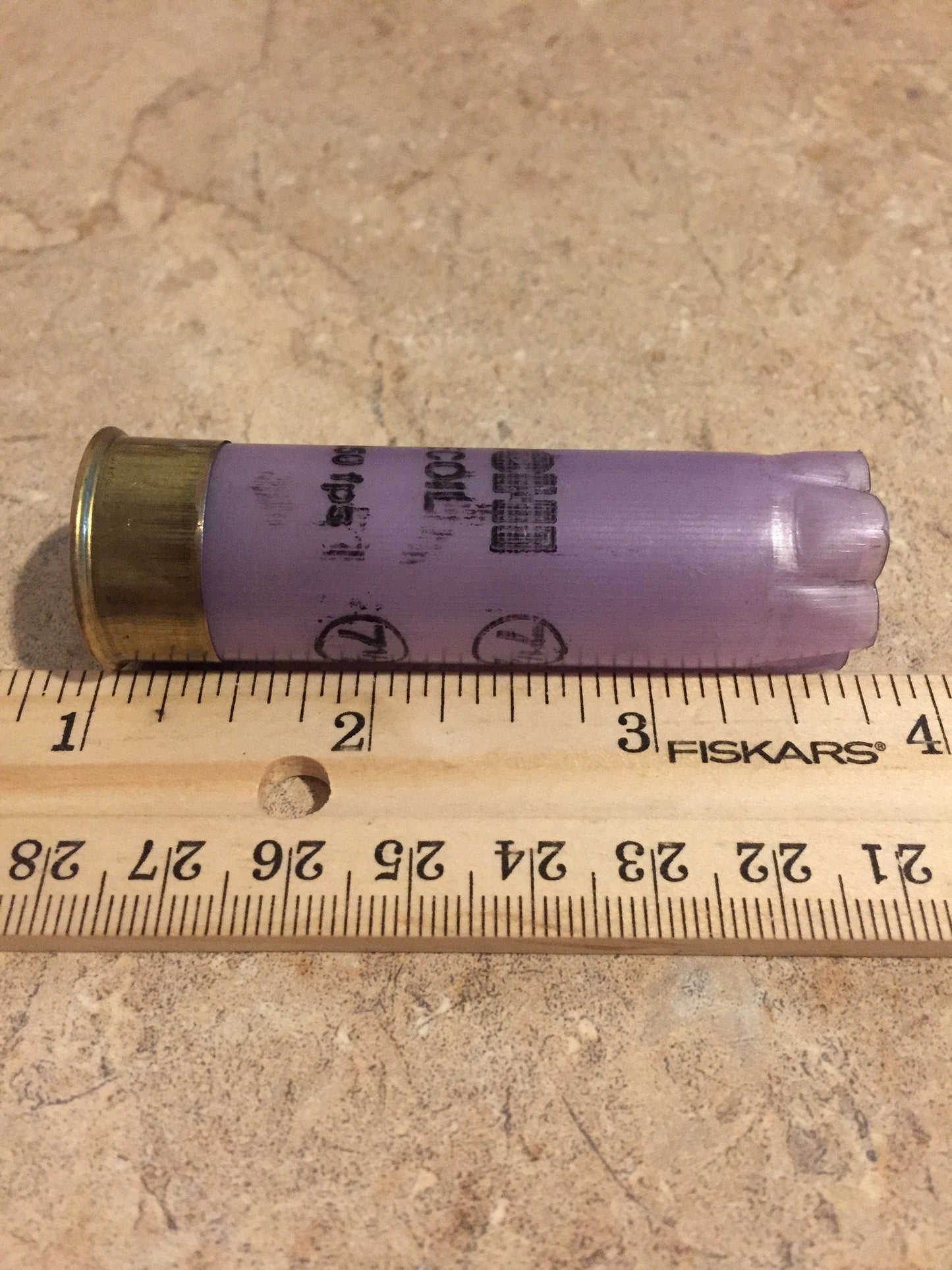 Purple Fiocchi Low Recoil 12 gauge shotgun shell measured on a ruler at approximately 2.75 inches