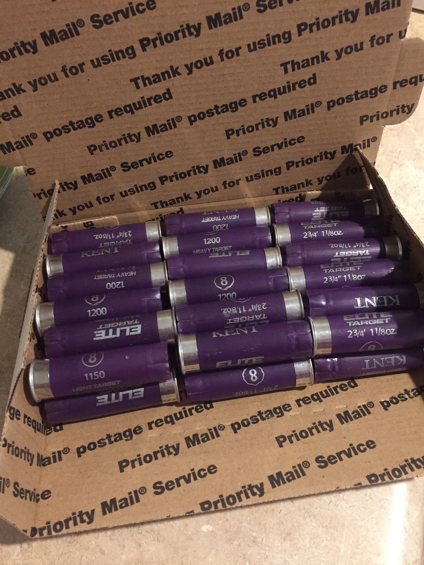 Rows of purple Kent shotgun shells packed inside a cardboard Priority Mail box