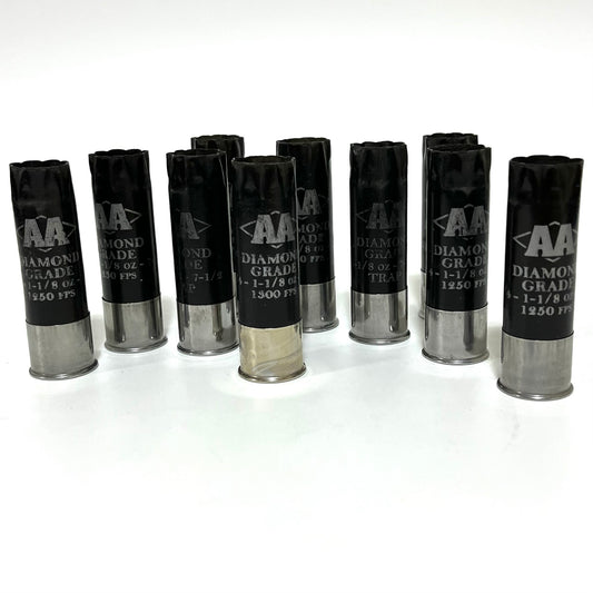 Row of eight empty black Winchester AA shotgun shells standing upright on a white surface.