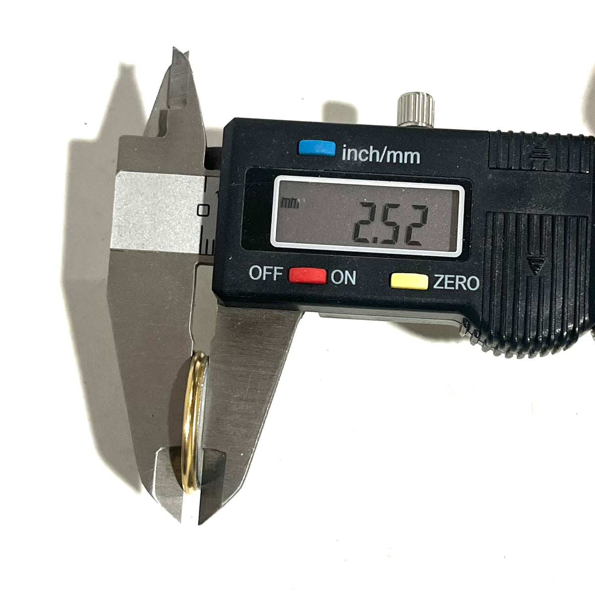 Digital caliper measuring the diameter of a gold flattened bullet slice ring at 2.52mm