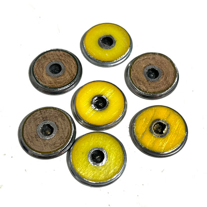 7 shotgun shell slices viewed from the hull side, 4 with yellow hulls and 3 with wood-tone hulls, arranged in a circle