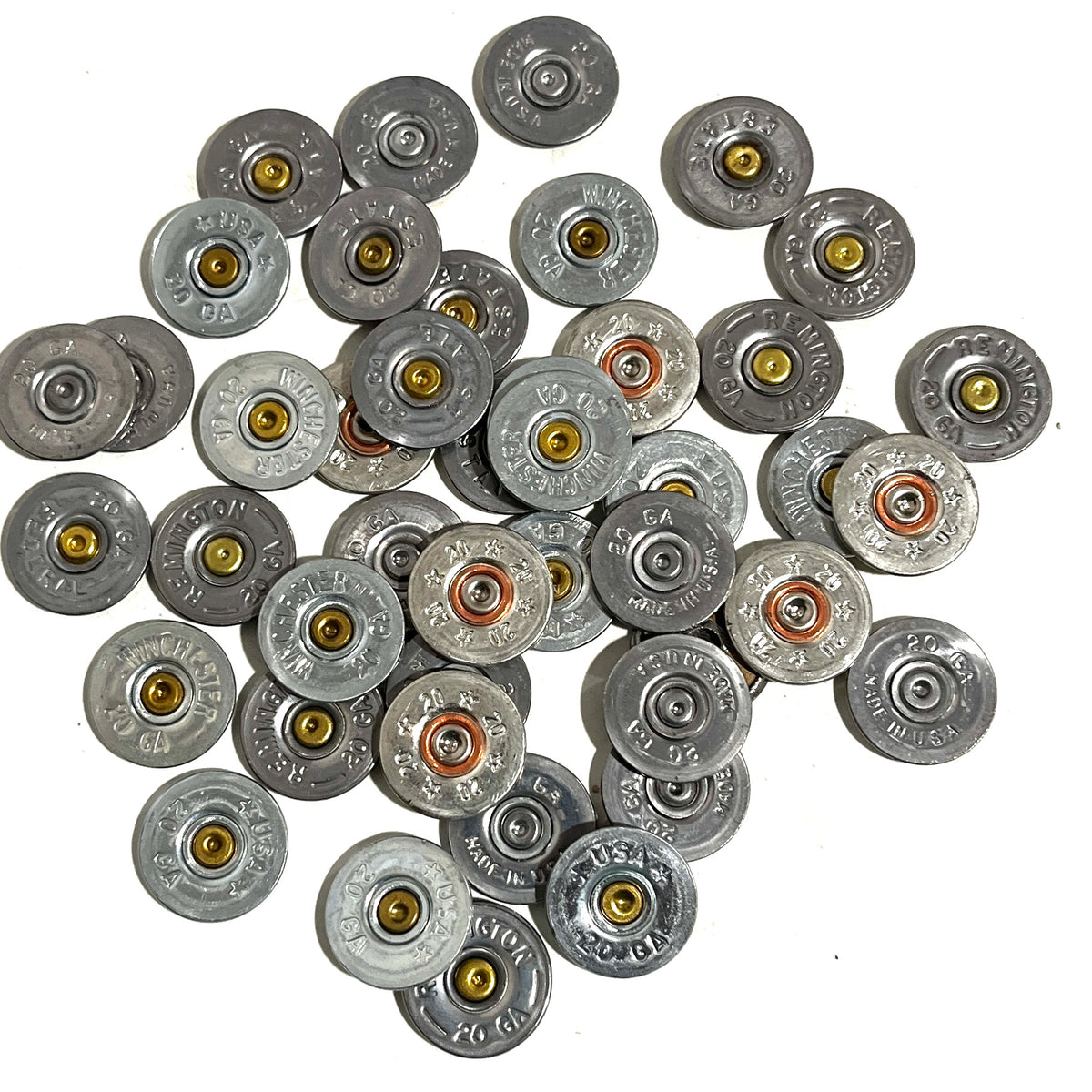 Pile of silver 20 gauge shotgun shell slices with various headstamps, on a white background