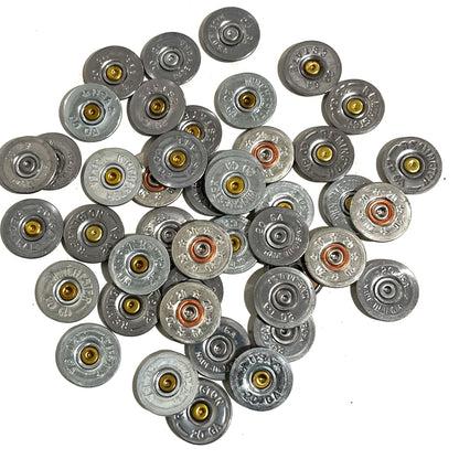 Pile of silver 20 gauge shotgun shell slices with various headstamps, on a white background