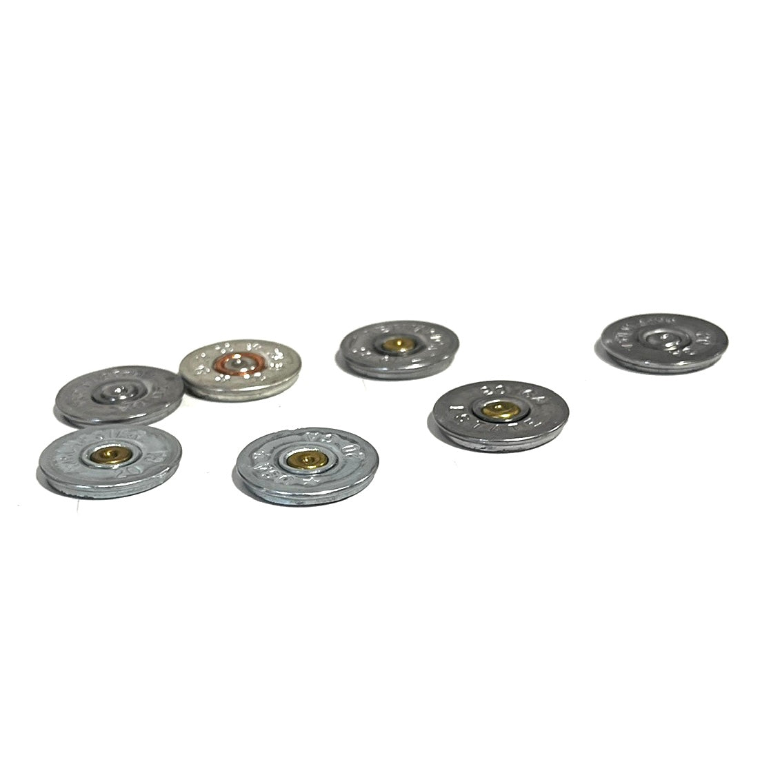 7 silver 20 gauge shotgun shell slices scattered on a white background