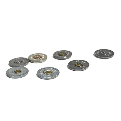 7 silver 20 gauge shotgun shell slices scattered on a white background