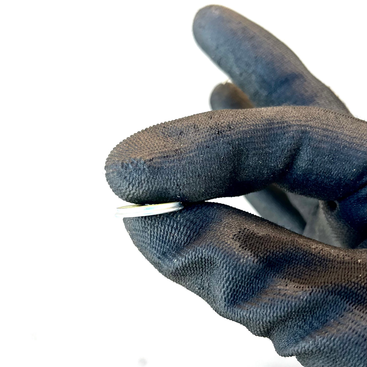 Thin edge of a Winchester 20 GA shotgun shell slice held between gloved fingertips