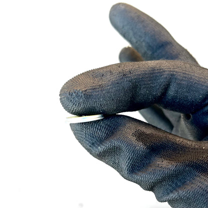 Thin edge of a Winchester 20 GA shotgun shell slice held between gloved fingertips