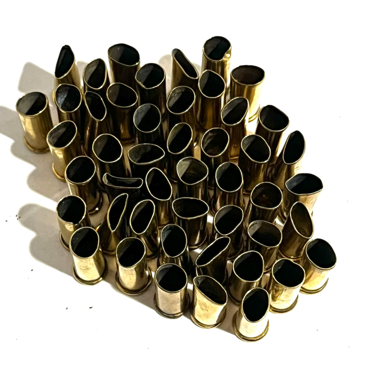 Rows of empty brass shell casings with black interiors standing open end up in neat rows