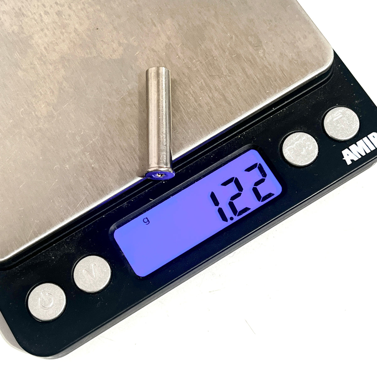 Nickel .22 caliber spent shell with drilled hole on a digital scale reading 1.22 grams white background