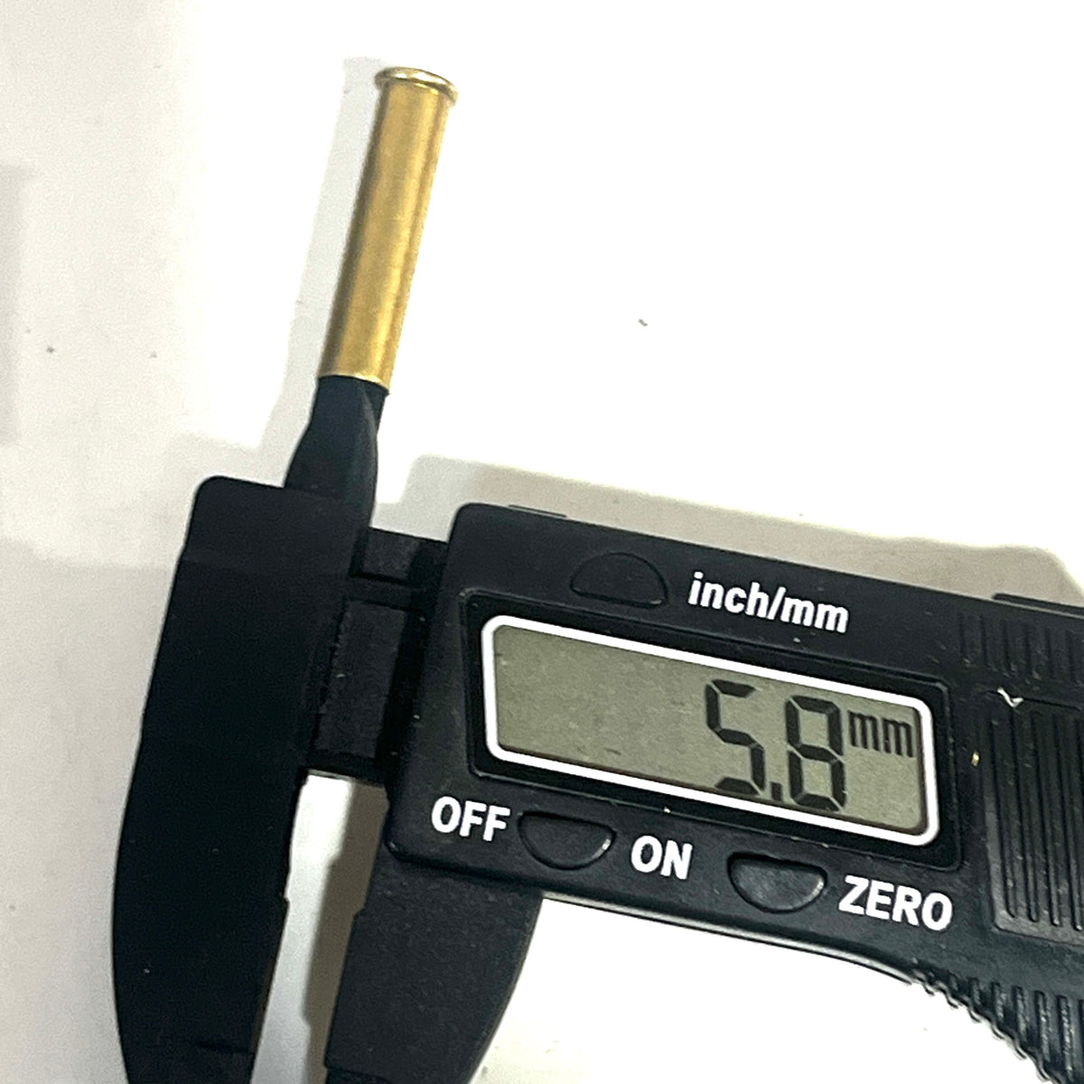 Digital caliper measuring the diameter of a brass 22 caliber WMR shell showing 5.8 mm