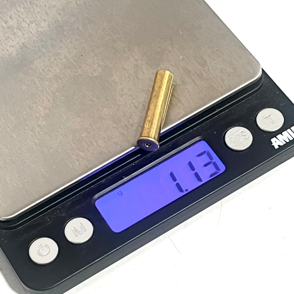 A brass 22 caliber WMR shell on a digital gram scale showing 1.13 grams