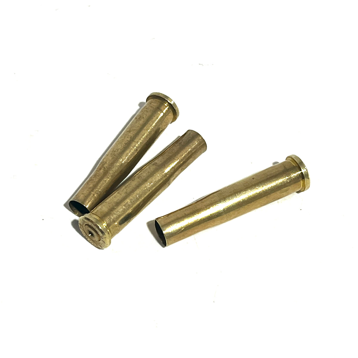 3 brass .22 Hornet shell casings lying on a white background