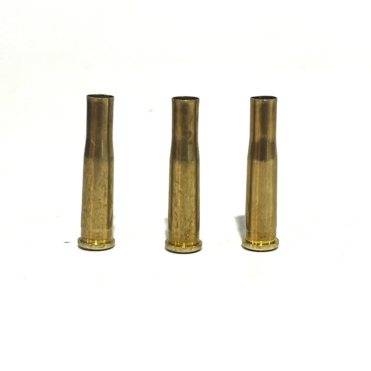 3 brass .22 Hornet shell casings standing upright with open mouths facing up, on a white background