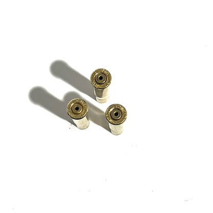 3 white-coated .22 Hornet shell casings viewed from the base showing drilled primer pockets