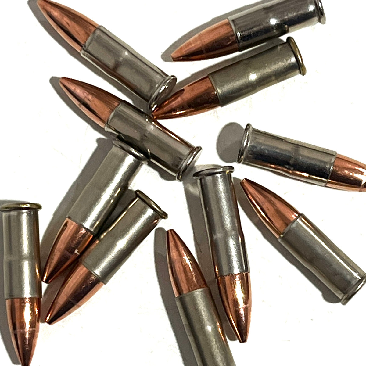10 .22 caliber nickel dummy rounds with copper bullets scattered on a white background
