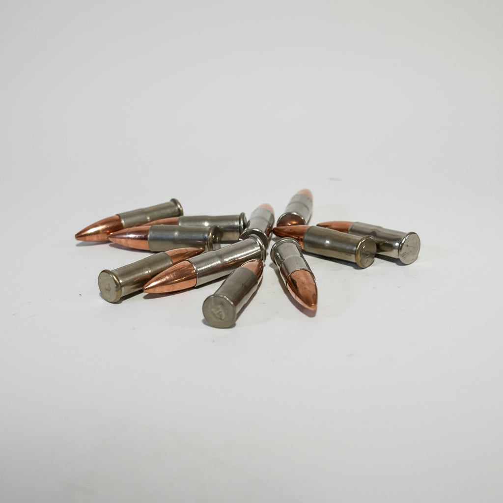 7 .22 caliber nickel dummy rounds scattered on a light gray background