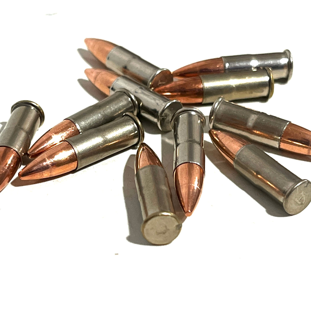 9 .22 caliber nickel dummy rounds scattered on a white background