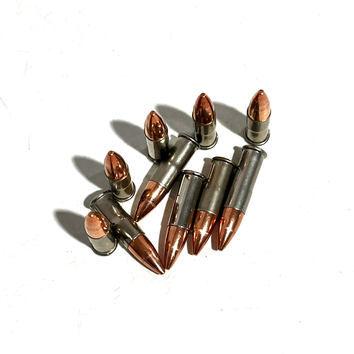 7 .22 caliber nickel dummy rounds scattered on a white background
