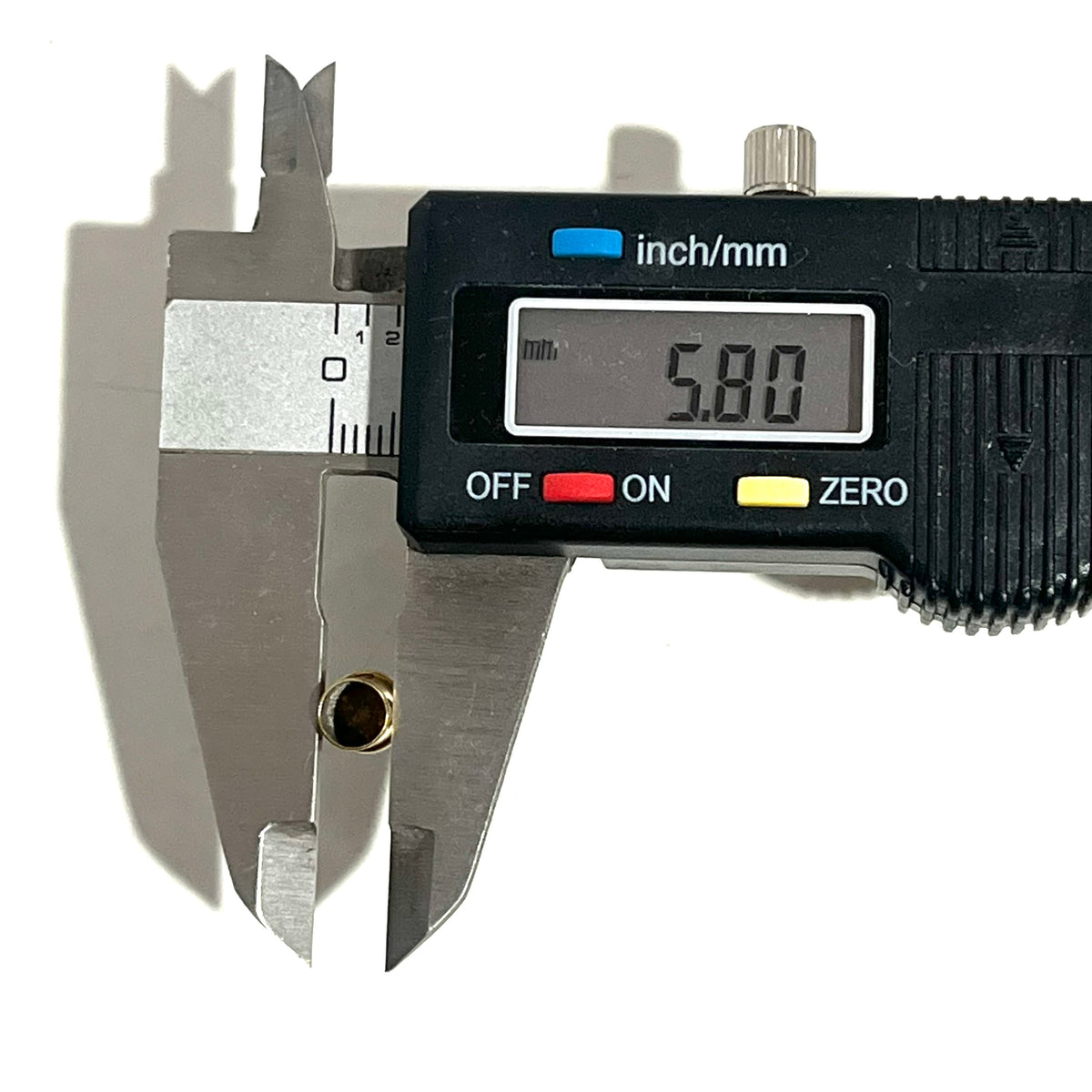 Digital caliper measuring the diameter of a brass shell casing showing 5.80 mm