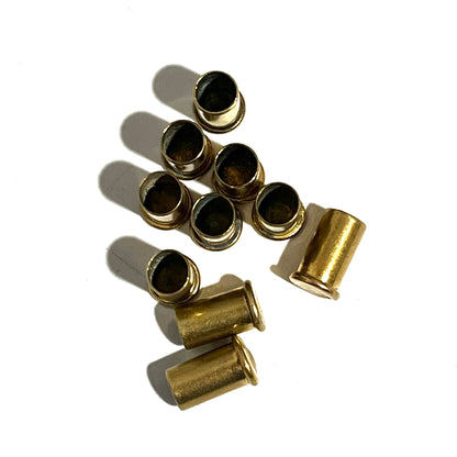 10 empty brass shell casings mostly standing open end up on a white background