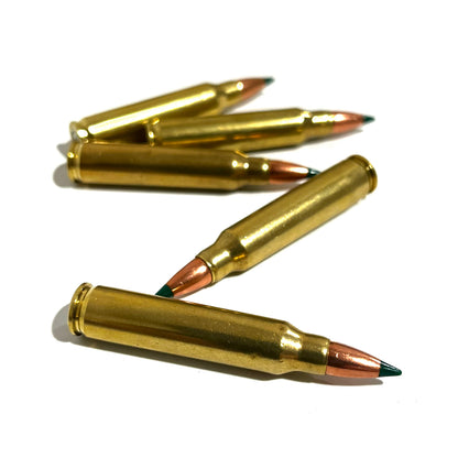 Five inert 5.56 dummy rounds with green tips on a white surface; two lie horizontally with two crossed in the middle.