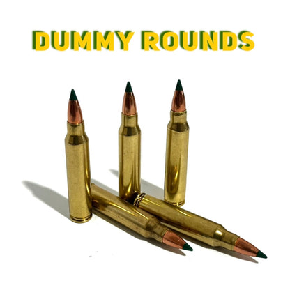 Three green-tipped 5.56 prop rounds standing behind two crossed ones, below yellow 3D 'DUMMY ROUNDS' text.