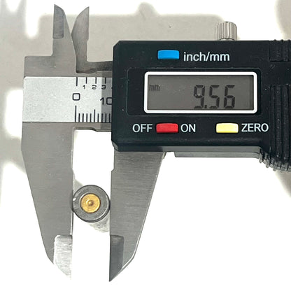 Digital caliper measuring the diameter of a gray steel .223/5.56 casing base at 9.56mm