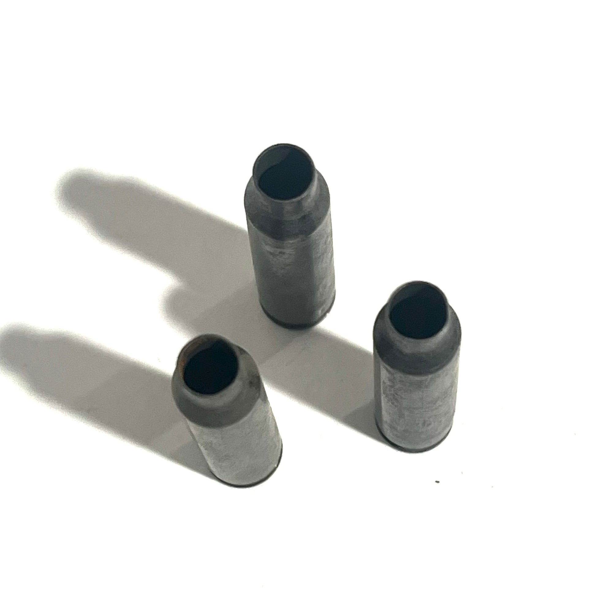 3 gray steel .223/5.56 spent casings standing upright viewed from open case mouth, white background